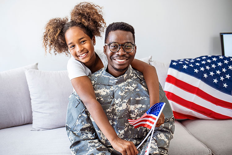 male soldier and daughter smiling on couch