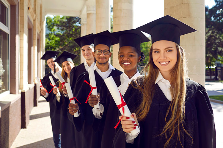 scholarship recipients holding diplomas in cap and gowns